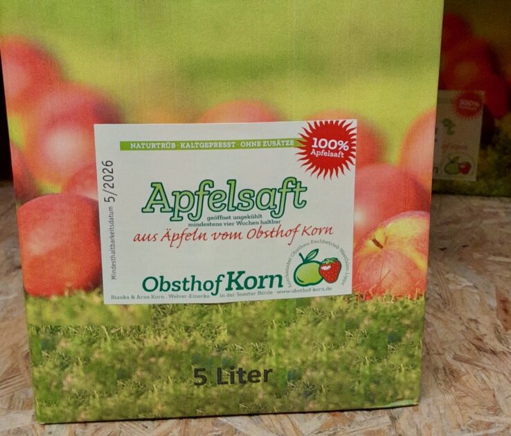 Selbstklebe-Etikett für Apfelsaft des Obsthof Korn, auf Rolle – natürliches, typografisch klares Design. Amateurfoto der fertig verpackten 5-Liter-Box.